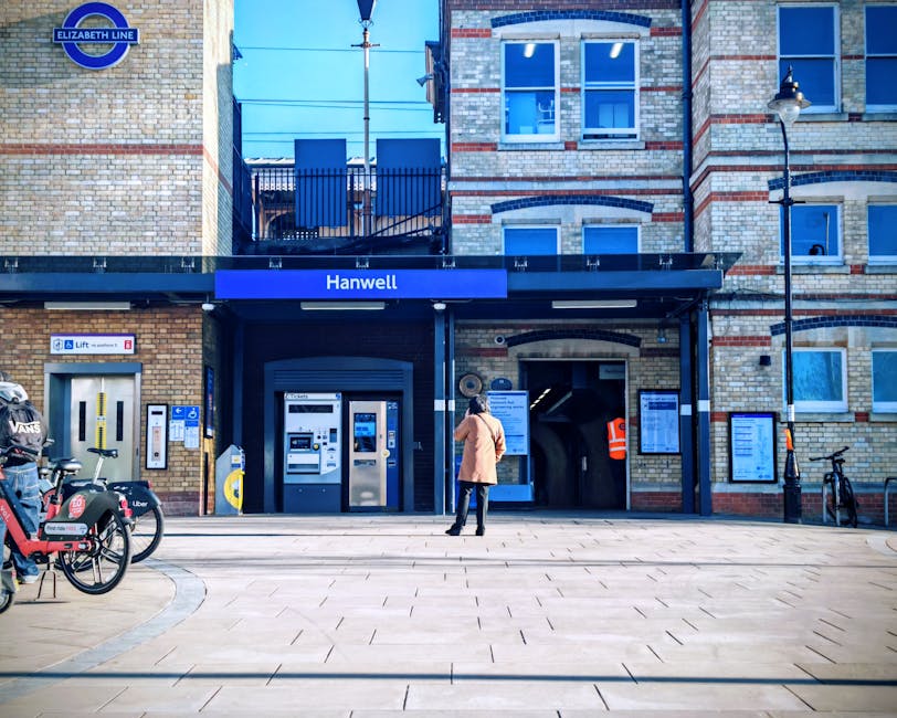 Barnes Bridge station platform featuring a modern commuter train with silver, red, and blue exterior parked alongside the tracks. The platform surface is clean and well-maintained, with tactile paving